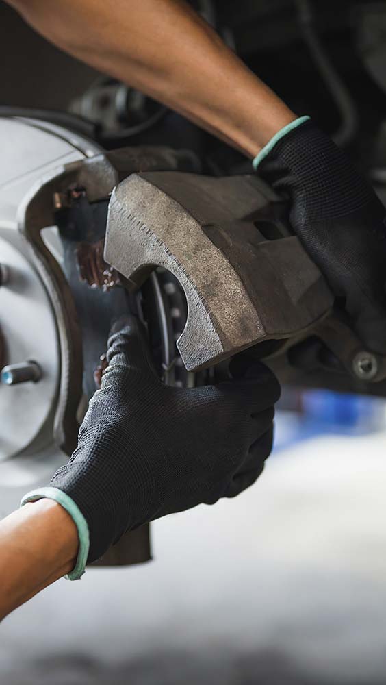 Brake repair service with a technician removing a brake caliper during maintenance.
