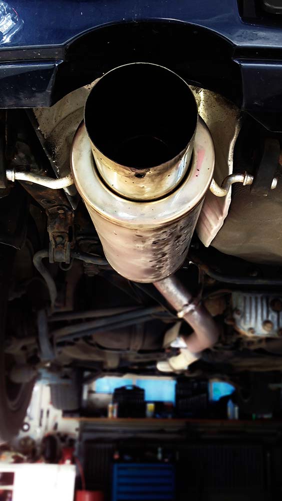 Exhaust and emissions system showing a muffler and exhaust pipe underneath a vehicle.