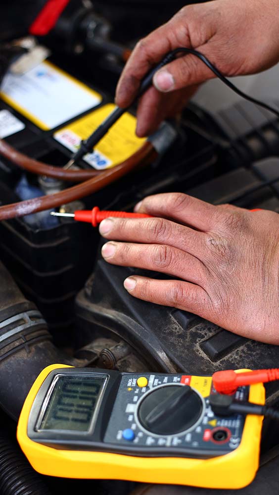 Programming and software updates testing vehicle battery voltage with a digital multimeter.