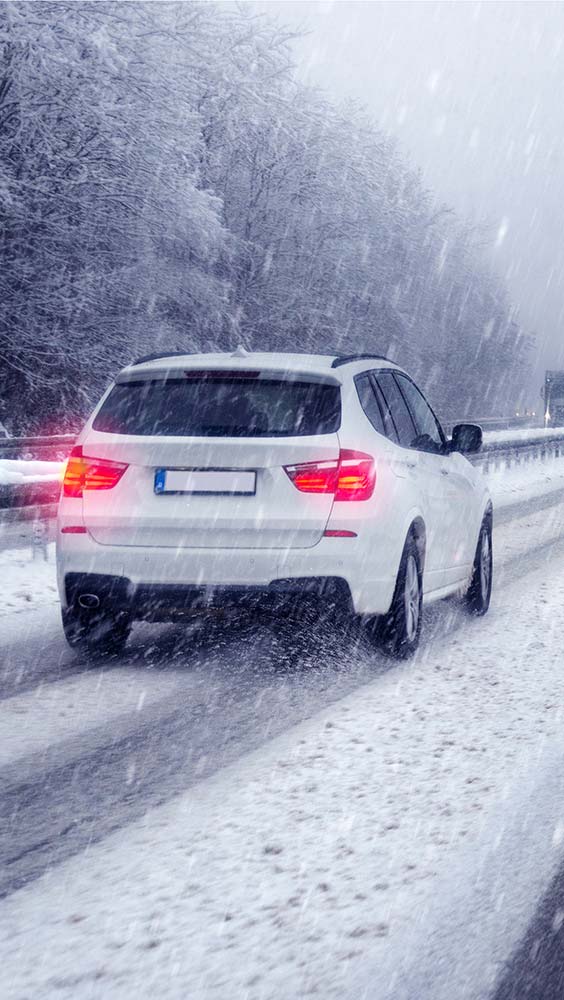 Tires and wheel services showing a vehicle driving in snowy conditions requiring proper tire grip.